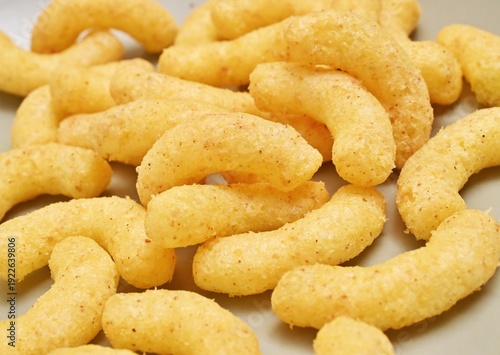 pile of many crunchy yellow corn puffs grouped together closely