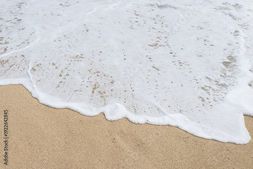 Fényképezés White sea foam washing over golden sand on a beach