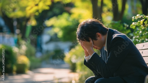公園のベンチで頭を抱える日本人男性