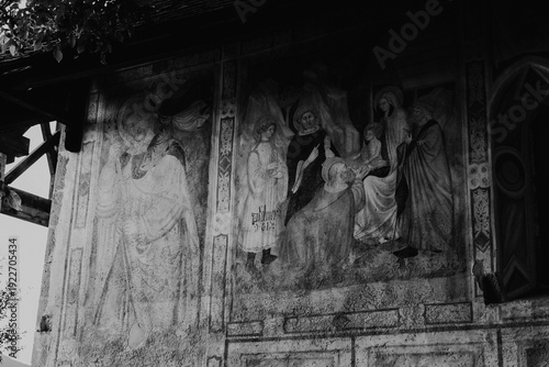 Ancient religious frescoes on the exterior wall of St. Valentin church with wooden benches, South Tyrol, Italy