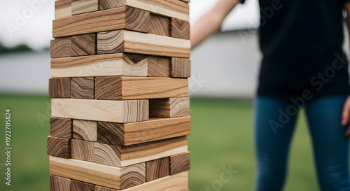 person playing a game of jenga with wooden blocks in a casual outdoor setting together