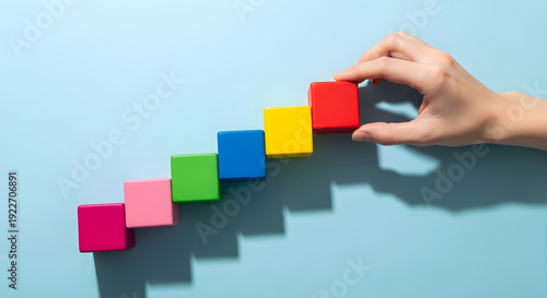 Hand placing wooden blocks in ascending order representing progress and achievement in creative projects.