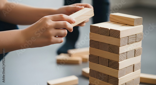 Person playing strategic game of jenga with wooden blocks and careful hand movements slowly