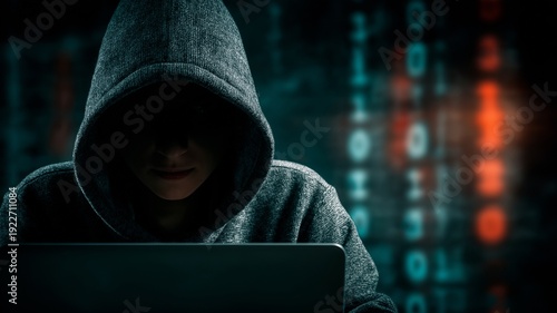 Hacker woman in a hood using a laptop in a dimly lit room with a backdrop of digital data