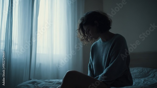 Depressed woman sitting on the bed at night, she is sad and suffering from insomnia