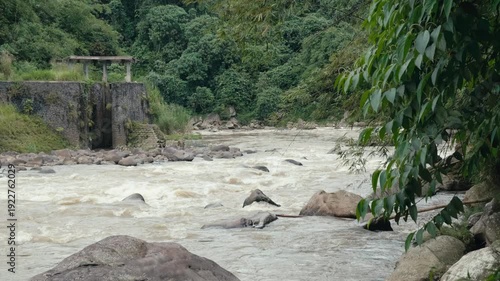 Powerful Turbulent Brown River Current Cascading Over Rapids and Rocks