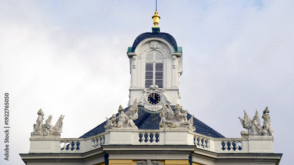 Fototapeta premium Bright yellow castle in Europe surrounded by fresh spring greenery and blooming trees. Soft daylight highlights the historic architecture and warm facade colors. Peaceful seasonal atmosphere makes the