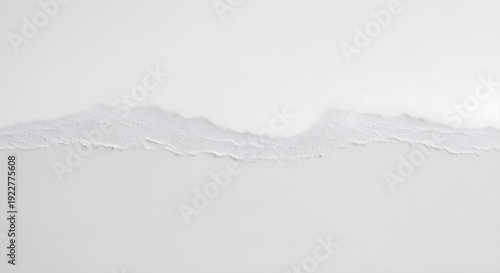Torn edge of white paper with rough texture and uneven boundary on plain white background surface
