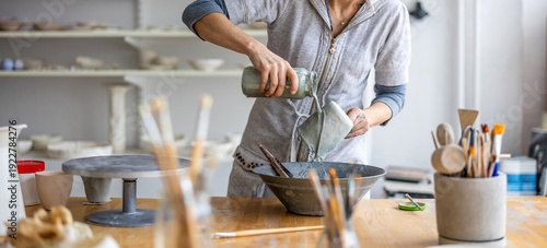 Close-up of an artist working with paint in a pottery workshop
