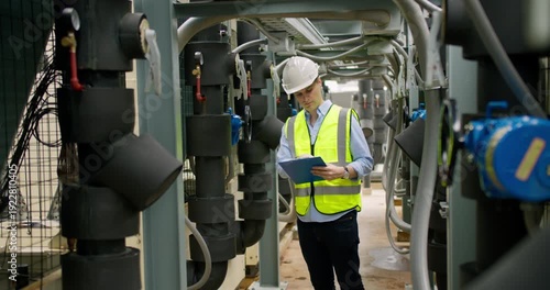 Professional industrial engineer is inspecting pipeline machinery in a modern facility, focusing on structural safety, strict quality control and optimizing daily operations.