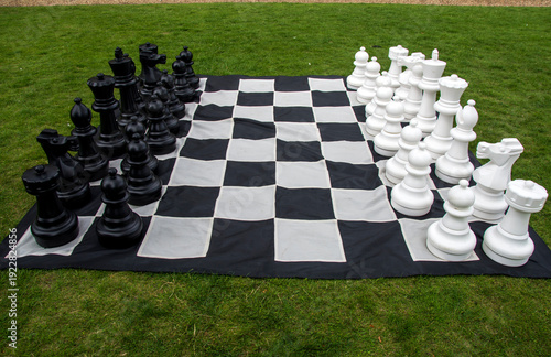 Schilderij op canvas oversized outdoor Chess set arranged on a large black and white checkered mat pl