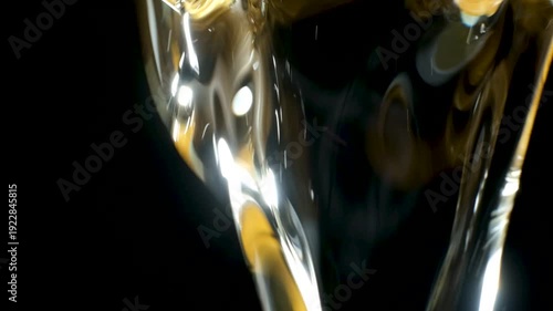 Refined sunflower oil pouring, slow motion on black background