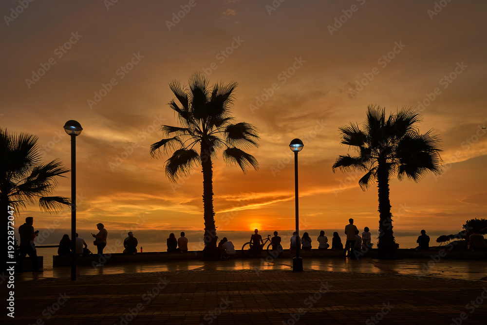 Obraz premium Romantic couples and retired travelers enjoying a vibrant summer sunset along the Malecón in Miraflores, Lima, Peru, capturing an active coastal lifestyle, scenic ocean views, and relaxed urban leisur