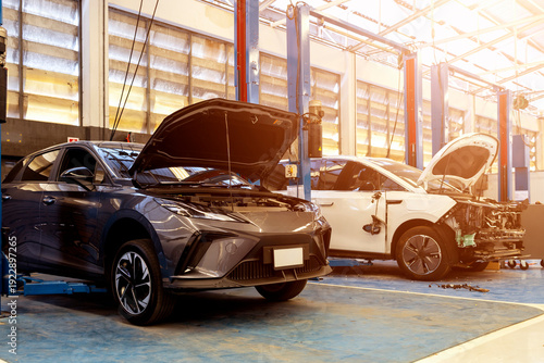 Modern white electric vehicle with side damage in a professional repair service center.