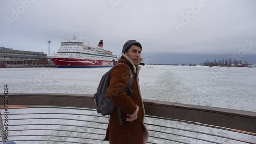 Wallpaper Mural A tourist man stands on a boat, observing the frozen Baltic Sea as it stretches between Helsinki and Suomenlinna. Torontodigital.ca