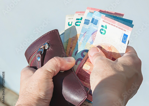 Leather wallet and euro banknotes in a woman's hands, selective focus.	