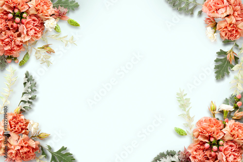Fresh carnation flowers, leaves and berries arrangement on light blue background, top view. Floristic frame decoration. Natural floral background.
