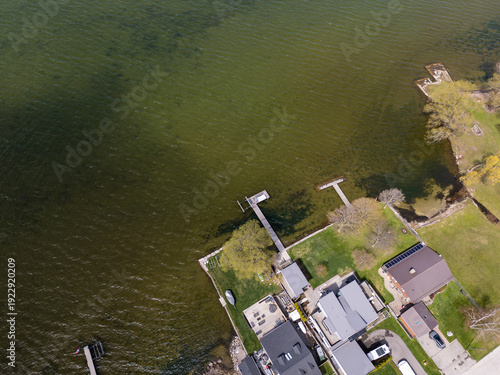 Aerial view showing a busy waterfront neighborhood with private docks extending into lake simcoe, showcasing real estate and a popular resort destination in georgina, ontario, canada