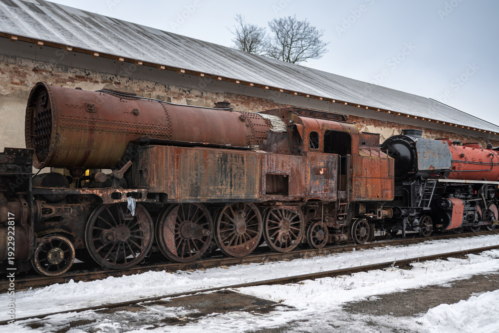 Obraz premium Rusty Abandoned Steam Locomotive in Winter Railway Yard