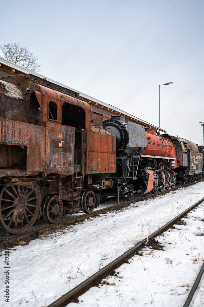 Obraz premium Rusty Abandoned Steam Locomotive in Winter Railway Yard