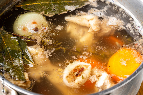 Photos Meat or chicken broth with bay leaf, carrots, and onions simmers in a saucepan