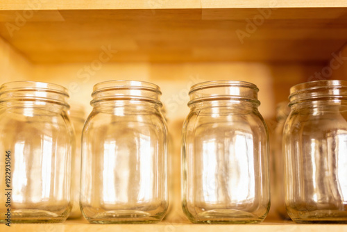 Empty glass jars on a wooden pantry shelf for kitchen storage