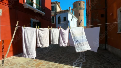 Burano street with laundry washed clothes hanging out to dry on ropes.