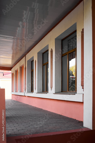Modern building facade with windows and perspective walkway under covered corridor