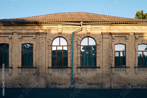 Historic brick building facade with arched windows symmetry and warm sunlight