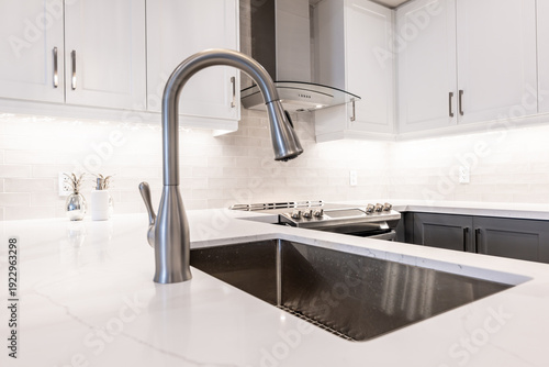 Kitchen showcasing a newly renovated contemporary interior with a brushed stainless steel faucet, undermount sink, white quartz countertop, and bright subway tile backsplash