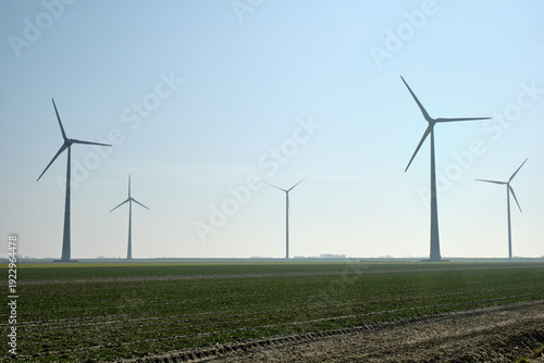 Quadro su tela Wind farm near Eemshaven, Netherlands with tall turbines in open field