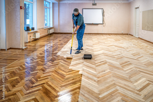Принти на полотні Worker in blue overalls uses a roller to coating floors