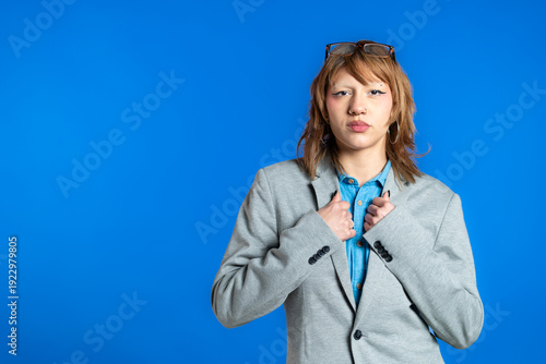 Confident young person posing in blazer on blue background