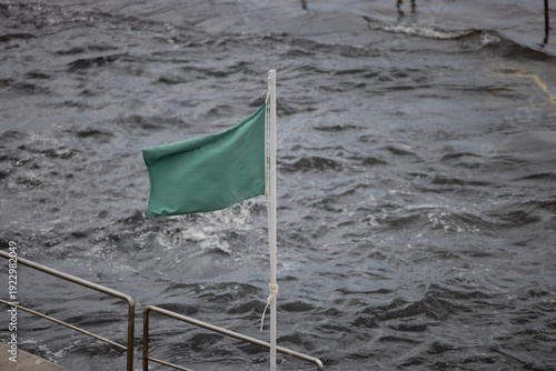 Bandeira verde num mastro de aviso numa piscina natural na Ilha Terceira, Açores