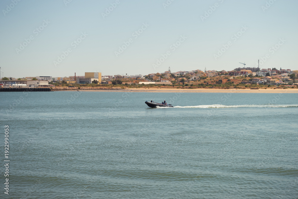 Obraz premium Semi-rigid boat or Zodiac sailing off the coast in the Portuguese Algarve. Recreational motorboat cruising on a sunny day.