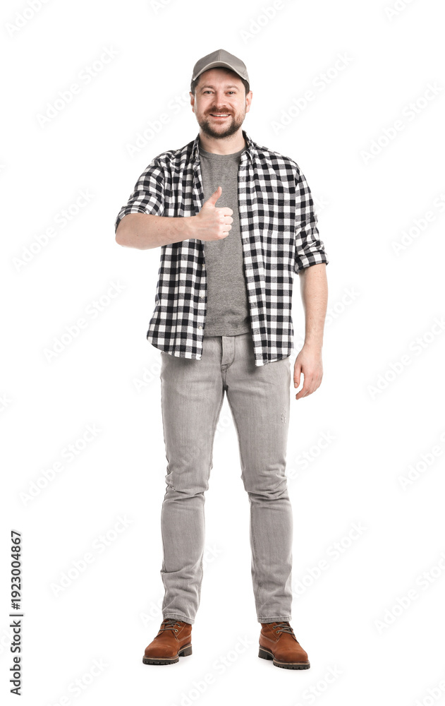 Fototapeta premium Smiling long-haul truck driver in baseball cap and checkered shirt showing thumbs up on white background