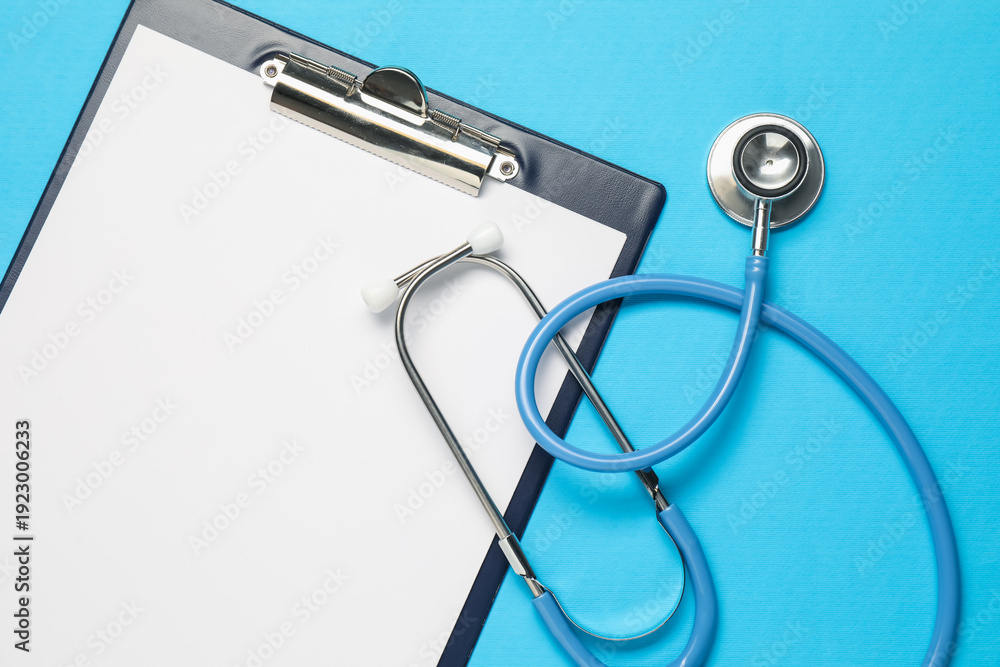 Fototapeta premium Stethoscope and clipboard on light blue background, top view