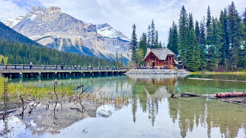 Foto Panoramic view of crystal clear Emerald Lake with a rustic wooden lodge and snow-capped mountains in Yoho National Park, Canada