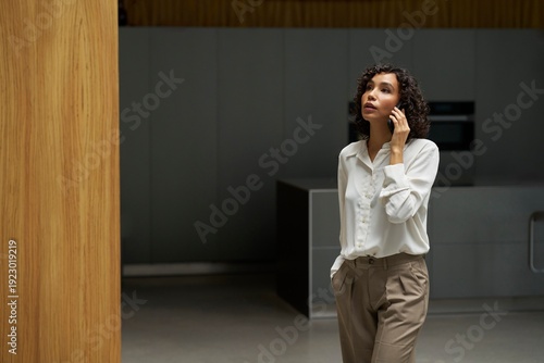 Woman Talking on Phone in Modern Office Setting During Daytime