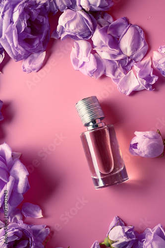  perfume bottle around may roses against pink background. beauty background