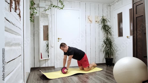 Caucasian man performing an abs wheel rollout exercise at home. Movement emphasizes core strength, stability and endurance, showcasing the concept of functional training and fitness improvement. 4k.