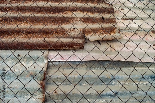 Foto A distressed scene features a chain link fence over a corrugated metal backgroun