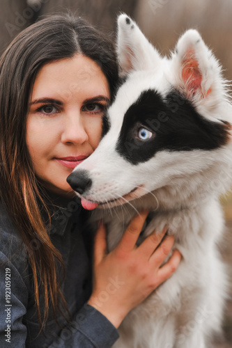 Woman holding Yakutian Laika dog portrait outdoors