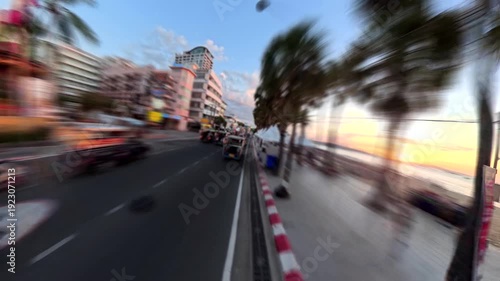 PATTAYA, THAILAND - DEC 2025 : Aerial high angle driving view of Pattaya beach road and sea in sunset. Travel, tourism and beach vacation concept video. Time lapse shot.