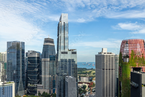 Modern glass skyscrapers of the Marina Bay financial district with sea and anchored ships visible in the background, Singapore