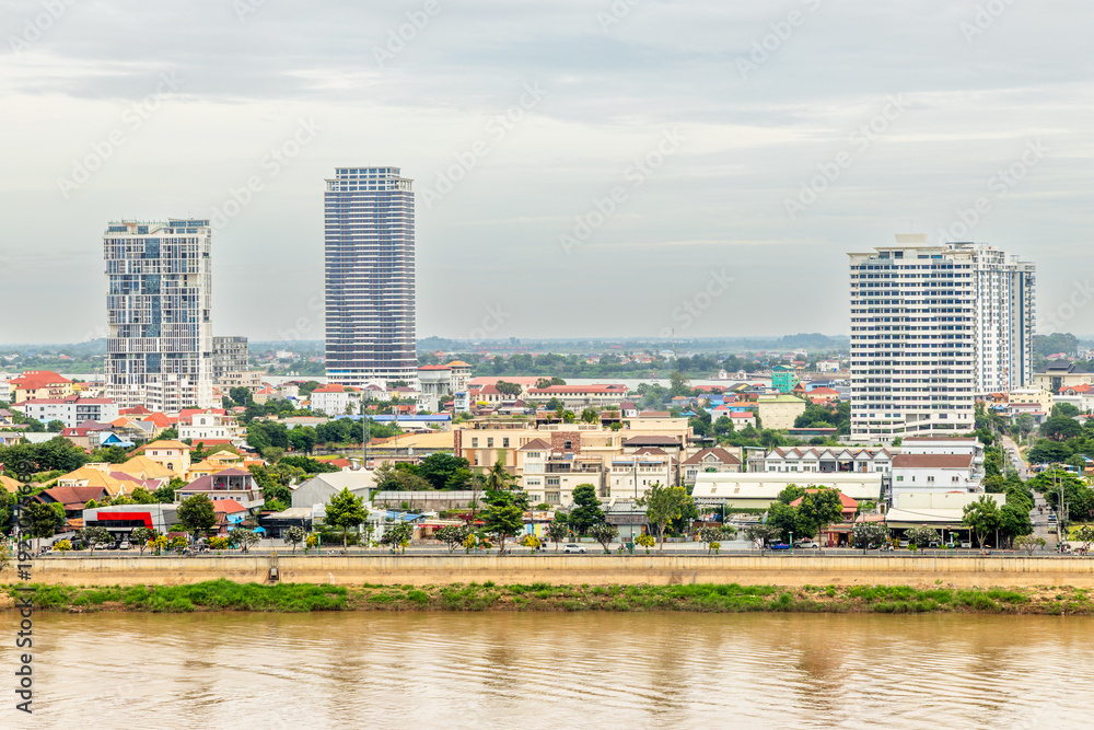 Obraz premium Modern apartment buildings rising above traditional houses along Tonle Sap riverbank in Phnom Penh, Cambodia