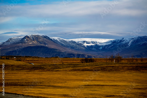 Panoramic view of snow-capped mountains and golden tundra fields in Akranes, Iceland