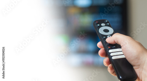 Hand holding television remote control with white background copy space, home media entertainment concept