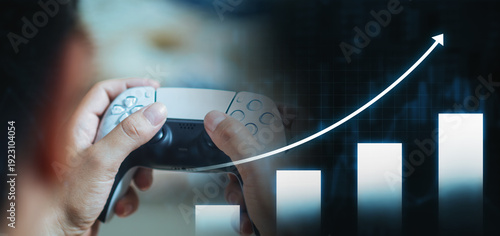 Gamer hands holding controller with rising financial stock market graph for gaming industry growth concept