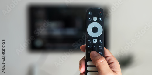 Person pointing smart remote control at television screen for streaming media entertainment concept